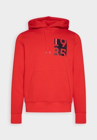 Punainen huppari, jossa on etutasku, musta graafinen suunnittelu, johon on merkitty numerot "1985", ja narut. Valmistettu pehmeästä kankaasta, jossa on resorit.