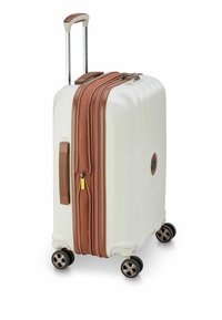 Valigia rigida bianca con dettagli marroni, doppie cerniere, manico estraibile e quattro ruote per la mobilità. Design da viaggio compatto.