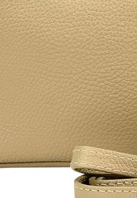 Beige leren portemonnee met een gestructureerd oppervlak, voorzien van een gevouwen riemdetail en eenvoudige stikselaccenten.