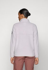 Hele hall fleece'i pullover, millel on kõrge krae, pikad varrukad ja horisontaalne õmblemine selja taga; vasakul varrukal on logo silmus.
