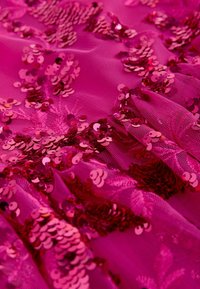 Fuchsia stof med palietter i forskellige nuancer af pink, med et tekstureret, lagdelt design og blomsterprint.