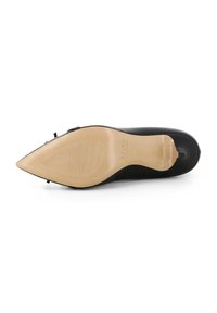Scarpa nera con tacco alto e punta affusolata, tomaia liscia e suola beige testurizzata. Presenta un delicato embossing e un accento a fiocco minimalista.