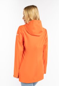 Vattentät orange jacka med huva, med långa ärmar, en slät textur och tryckknappdetaljer vid ärmsluten.