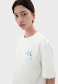 Witte katoenen T-shirt met korte mouwen, voorzien van een blauwe grafische print op de borst. Gladde textuur, relaxed fit met een ronde halslijn.