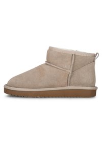 Botines de ante beige con puntera redondeada, costuras cosidas y suela de goma plana con un dibujo texturizado. Incluyen un lazo para facilitar su puesta.