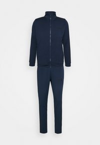 Veste bleu foncé zippée intégralement avec col montant et pantalon slim assorti, tous deux avec des logos subtils de la marque sur la poitrine et la cuisse.