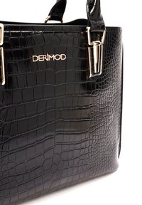 Sac à main noir en simili-crocodile, fabriqué en matériau brillant. Équipé de ferrures dorées avec le nom de la marque "DERIMOD" affiché en évidence.