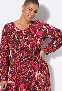 V-Ausschnitt, langärmliges Kleid mit einem lebendigen Blumenmuster in den Farbtönen Pink, Rot und Schwarz; tailliert und mit fließendem Rock.