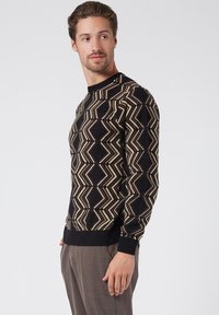 Maglione nero con motivo geometrico in crema e taupe, dotato di polsini e orlo a coste per un look aderente.