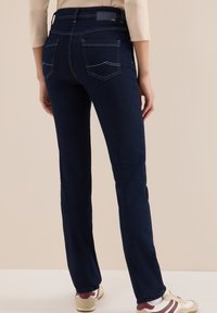 Donkerblauwe denim jeans met een rechte pijp, twee achterzakken en een hoge tailleband. Opvallende stikselaccenten op de zakken.