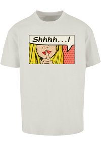 Camiseta blanca de algodón con un diseño de pop art de una mujer con cabello largo y rubio, con un dedo contra los labios, diciendo "Shhhh...".