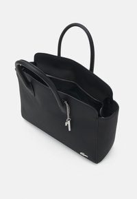 Borsa tote nera con trama liscia, manici doppi, chiusura con zip e tasca interna. Presenta un ciondolo e un logo in argento.