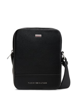 Kompakte schwarze Crossbody-Tasche aus strukturiertem Leder mit verstellbarem Riemen, silbernem Reißverschluss und Tommy Hilfiger-Logo auf der Vorderseite.