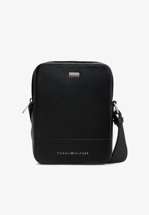 Kompaktowa czarna torebka na ramię ze skóry o fakturze, z regulowanym paskiem, srebrnym zamkiem błyskawicznym i logo Tommy Hilfiger na przedniej stronie.