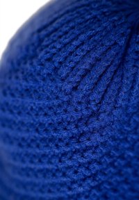Blue knitted beanie with a textured pattern, featuring a ribbed style and soft, wool-like material. Close-up view of the stitching.