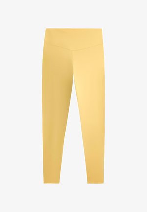 Žute helanke s visokim strukom, glatke teksture i bez vidljivih uzoraka ili logotipa, prikazane na bijeloj pozadini.