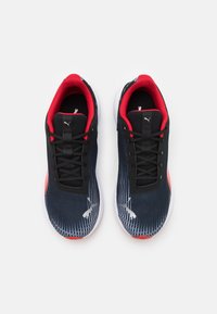 Černé sportovní boty s textilem z jemné síťoviny a gradientním vzorem, červenými akcenty a bílou podrážkou. Šněrování s logem na bocích.