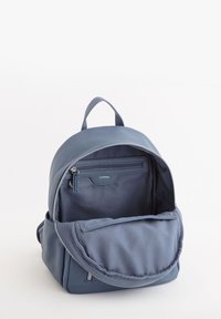 Sininen teksturoitu nahkareppu, jossa on vetoketjukiinnitys, tilava sisustus ja etutasku, jossa on lisävetoketjutasku.