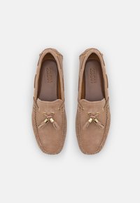 Suede moccasin shoes in light brown with gold-accented laces and a smooth leather insole. Features traditional stitching and a rounded toe.