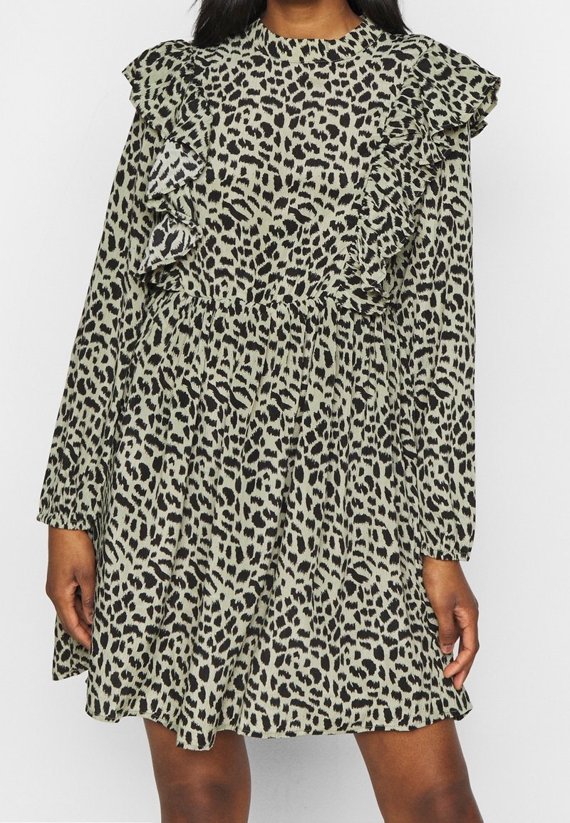 Robe longue verte à manches longues avec un col volanté et un imprimé léopard noir. Elle présente une taille cintrée et une jupe fluide. Tissu doux et léger.