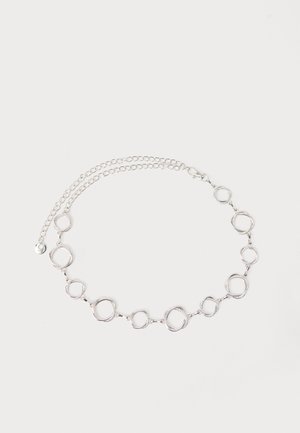 Zilveren ketting met schakels bestaande uit met structuur afgewerkte open cirkels die met elkaar verbonden zijn, en een verstelbare sluiting, op een witte achtergrond.