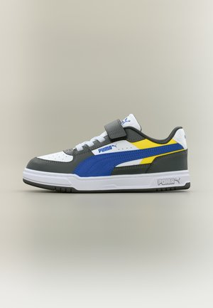 Nízký teniskový model Puma s panely v bílé, šedé, modré a žluté barvě, bílými tkaničkami a páskem na suchý zip přes nárt.