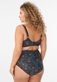 Divdaļīgs peldkostīms ar ziedu rakstu tumši tējas krāsā ar zemu aizmuguri. Aprīkots ar biezām lencēm un pilnībā pārklājošu augstu jostasvietu.