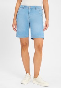 Lichtblauwe denim shorts met een rechte snit, omgeslagen zoom en voorzakken. Gecombineerd met witte sneakers. Gladde textuur.