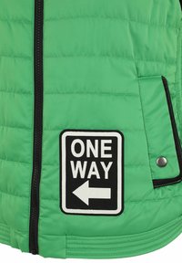 Grüne Pufferjacke mit einem gestepperten Muster, ausgestattet mit einem schwarzen Reißverschluss und einem "ONE WAY" Aufnäher mit einem Pfeil, akzentuiert durch schwarze Anpassungen.