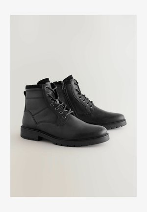 Stivaletti neri in pelle con lacci e zip laterale, caratterizzati da pannelli testurizzati e una suola in gomma resistente, progettati per durata e supporto.