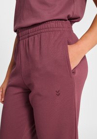 Bordowe bawełniane spodnie dresowe z elastycznym pasem, bocznymi kieszeniami i subtelnym wyszywanym logo w kształcie jodełki na nodze.