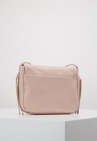 Rosa Leder-Umhängetasche mit glatter Textur, Reißverschluss und einer Vorderseite Tasche. Verfügt über einen abnehmbaren Riemen und minimalistisches Design.