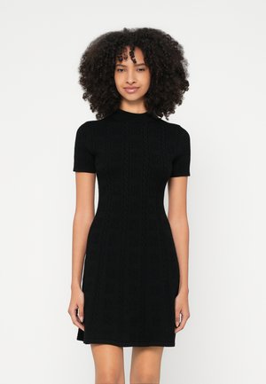 Mustast kootud kleit lühikeste varrukatega, millel on soonikmustriga ja kõrge kaelusega, keha jälgiv siluett ning tekstuuriga kangas.