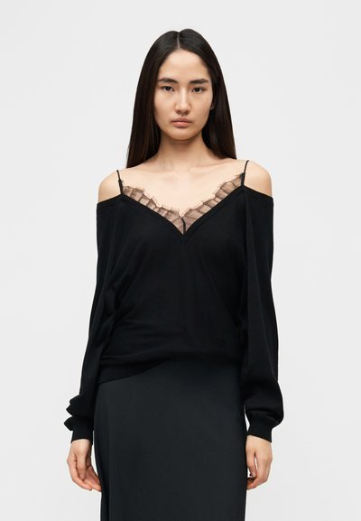 Haut noir décolleté épaules nues avec un détail en dentelle transparente au niveau du col. Comprend des manches longues et une coupe décontractée. Texture lisse sur toute la surface.