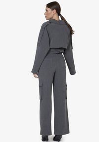 Grijze, op maat gemaakte cropped jacket met schouderdetails en wijde cargo broek met zakken. Glad textuur en gestructureerd ontwerp.