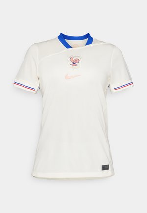 Vit Nike-tröja med blå krage. Har en tupp-emblem och subtila designinslag. Inkluderar röda och blå ränder vid ärmsluten.