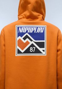 Felpa arancione con un grande grafico colorato che raffigura montagne e una forma a cuore, con la scritta 'NAPAPIJRI' e il numero '87' sul retro.