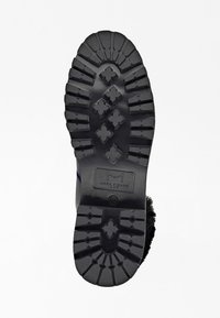 Svart gummistövelsula med djupa mönster och korsformade mönster, visar Marc Fisher LTD-logotypen och storlek 7M präglad.