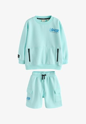Lyseblå børne-sweatshirt med sorte lynlåslommer og matchende shorts med cargolommer og snøre, mærket "BAKER NINETEEN EIGHT".