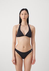 Melns bikinis komplekts ar kakla siksnu topu un trīsstūrveida kausiem, kā arī saskaņotas zemas vidukļa biksītes. Gluda tekstūra, minimālisma dizains, maza logo akcentācija.