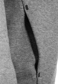 Grå bomullstyg med ribbad textur; har en svart accentpunkt. Nära bild av materialet som visar dess mjukhet och vävstruktur.