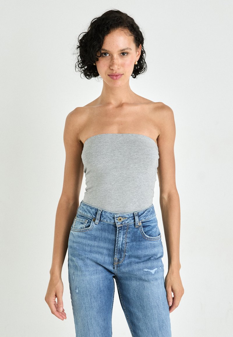 Grå topp uten stropper laget av mykt stoff, parret med høyhåndte lyseblå jeans. Slim fit med en glatt tekstur og minimalistisk design.