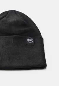 Gorro de punto negro con un dobladillo. Presenta un pequeño parche circular con el logo "Buff". Textura suave y ajuste ceñido.
