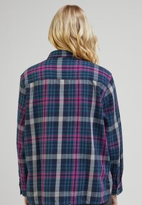 Rutigt skjorta i marinblått, grått och rosa. Den har lång ärm, knäppning vid ärmslut och en ryggsyd med en klassisk kragdesign. Slät tygtextur.