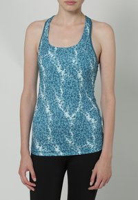 Blå linne med ett geometriskt mönster i varierande nyanser, gjort av ett lätt material. Utformat med racerback-stil för enkel rörelse.