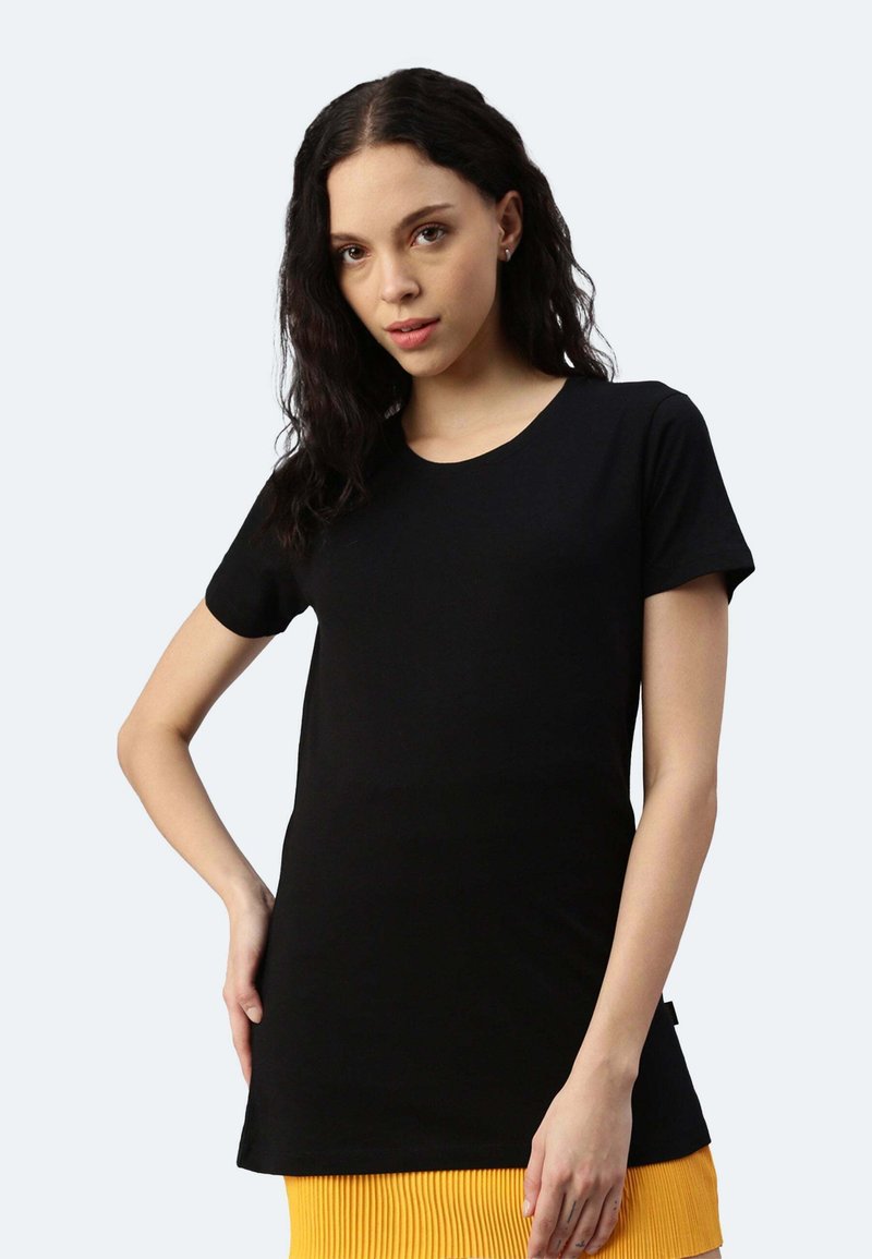 Schwarzes Kurzarm-T-Shirt aus weichem Stoff, mit klassischem Rundhalsausschnitt und gerader Passform. Einfaches Design, kombiniert mit einem gelben Rock.
