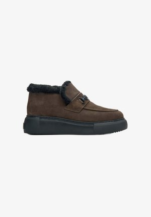 Bruine suede enkellaarsjes met een zwarte nepbont kraag, voorzien van een platte zwarte zool en decoratieve veters op de bovenkant.