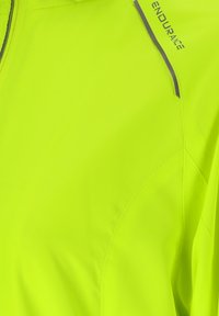 Høj-synlighedsgul sportjakke med refleksstribe og "ENDURANE" trykt nær skuldersømmen.