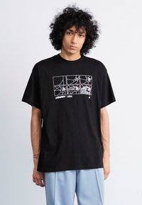 T-shirt noir surdimensionné avec un graphique de toiles d'araignée blanches. Matériel en coton doux, coupe décontractée, col rond, manches courtes.