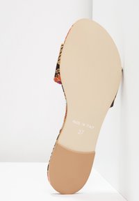 Plochá slip-on obuv s květinovým vzorem na svršku, černým základem, béžovou podrážkou a štítkem s nápisem "Vyrobeno v Itálii" a velikostí "37."